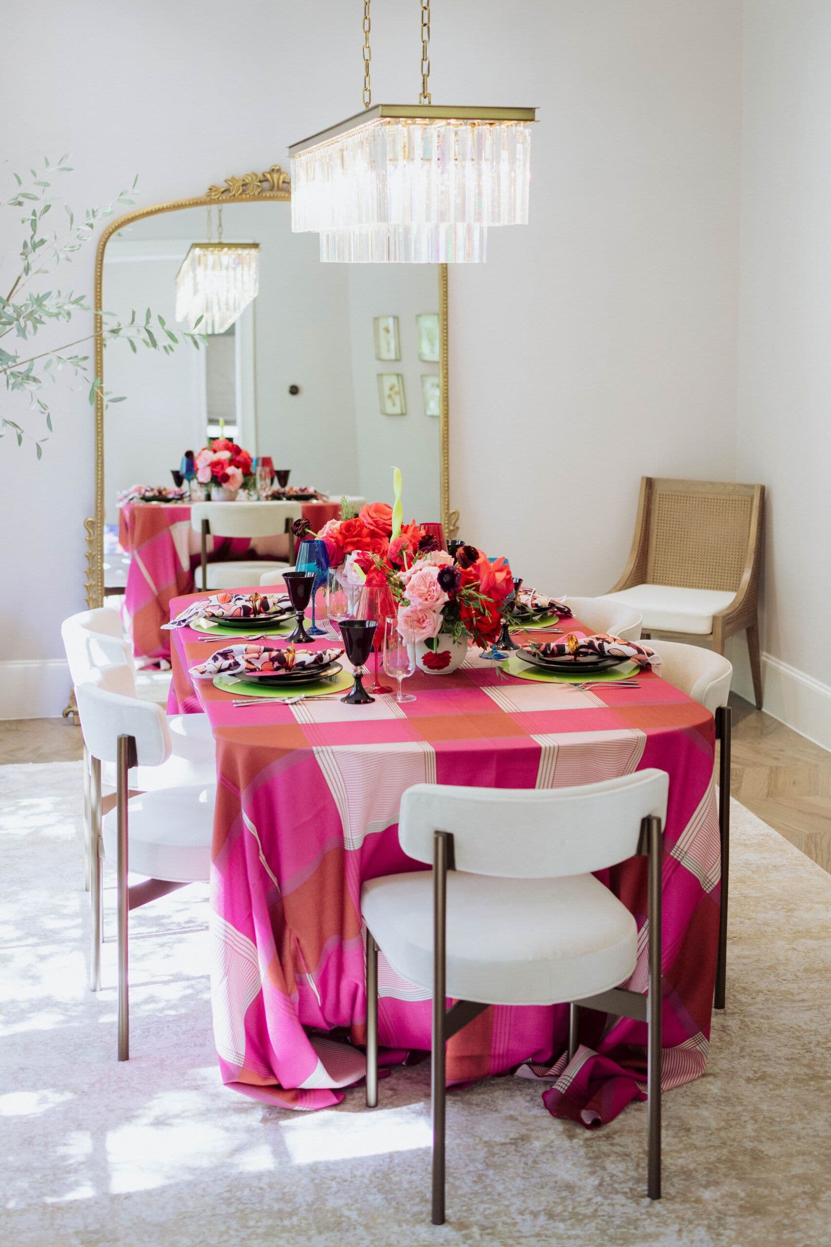 Holiday table setting with pink plaid tablecloth and colorful place settings